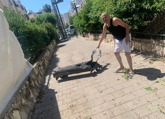 الفنان الإسرائيلي يشاي ليفي بجانب الصاروخ الذي سقط بفناء منزله جنوب تل أبيب