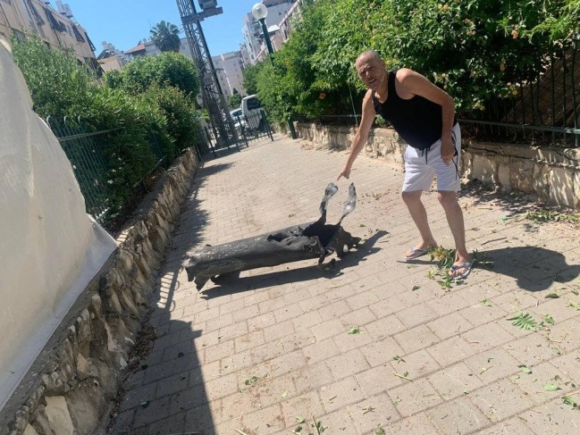 الفنان الإسرائيلي يشاي ليفي بجانب الصاروخ الذي سقط بفناء منزله جنوب تل أبيب